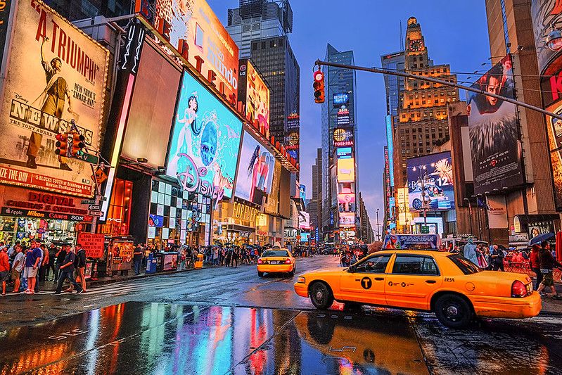 “Rain turns Midtown into a mirror—where history, ambition, and motion converge.”